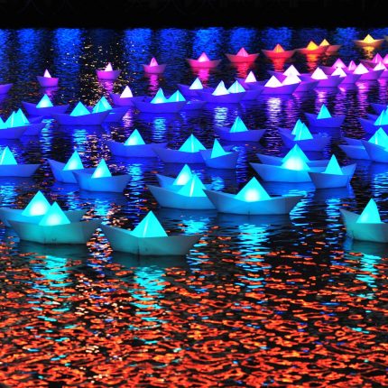 Aether & Hemera, Voyage. Image courtesy of Quays Culture. Origami boats floating on water. The boats are different colours - green, blue, purple, pink.