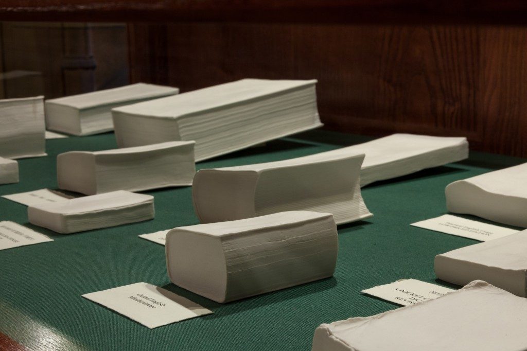 A display of porcelain books of various sizes, placed on a green surface.