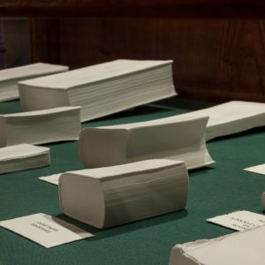 A display of porcelain books of various sizes, placed on a green surface.