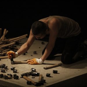 Man crouched over broken hammers.