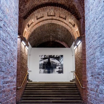 Stairs leading to a large photograph under a brick arch.
