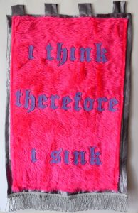 Pink wall hanging with the words 'i think therefore i sink' in purple letters.