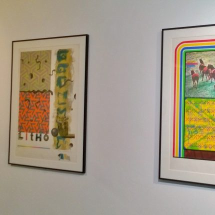 Photograph of three framed prints on a white gallery wall.