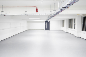 a large empty room with grey floor and white walls