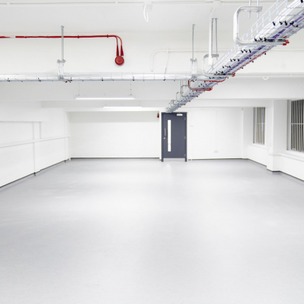 a large empty room with grey floor and white walls