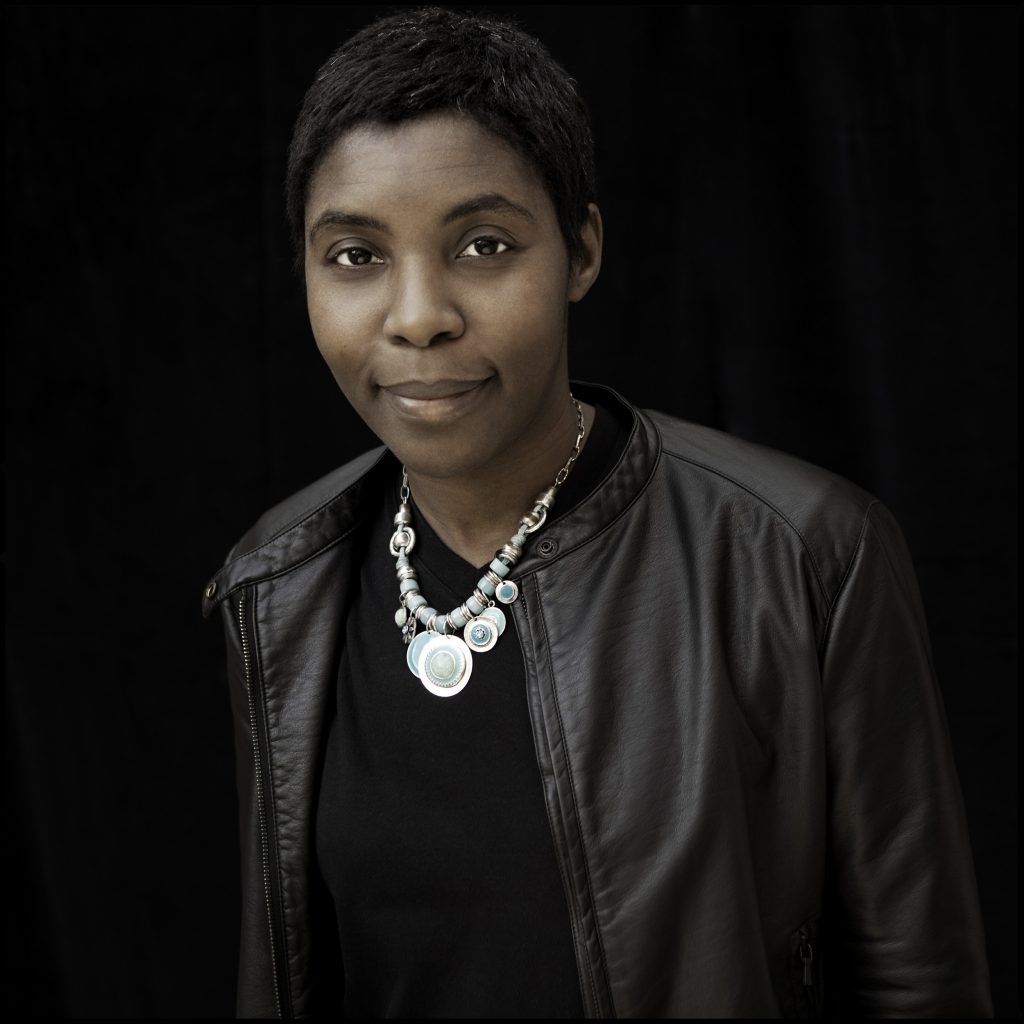 A profile photograph of Christine Eyene against a dark background.