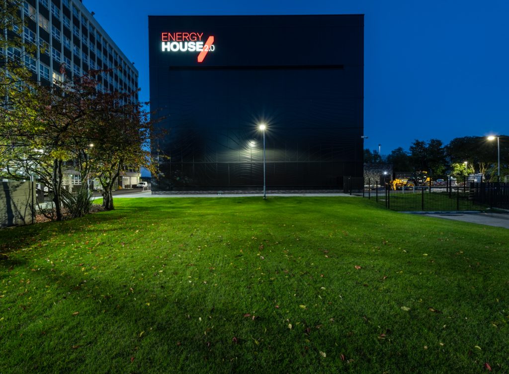 A vibrant image shows the Energy House 2.0 building illuminated at night.