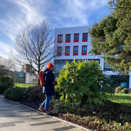 A photography shows Gwen Riley Jones walking around the University of Salford campus.