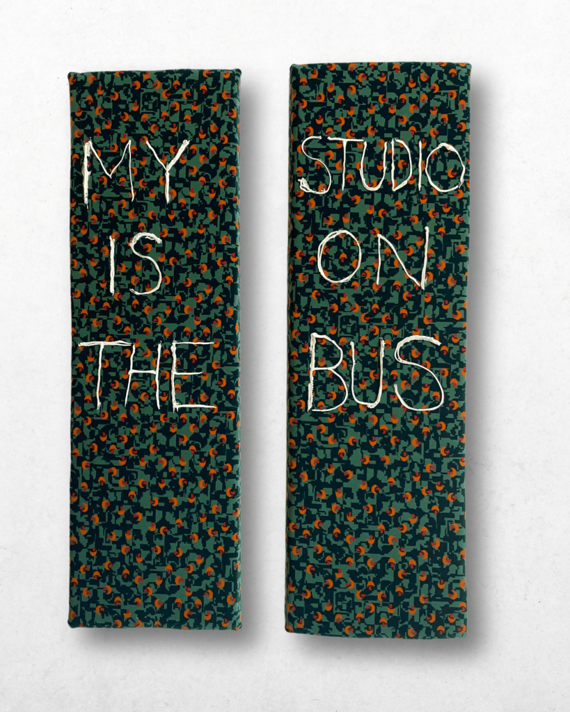 Two vertically hung rectangle forms, covered with green stagecoach style bus seat material, are decorated with lettering in white paint reading 'My Studio Is On The Bus'. 