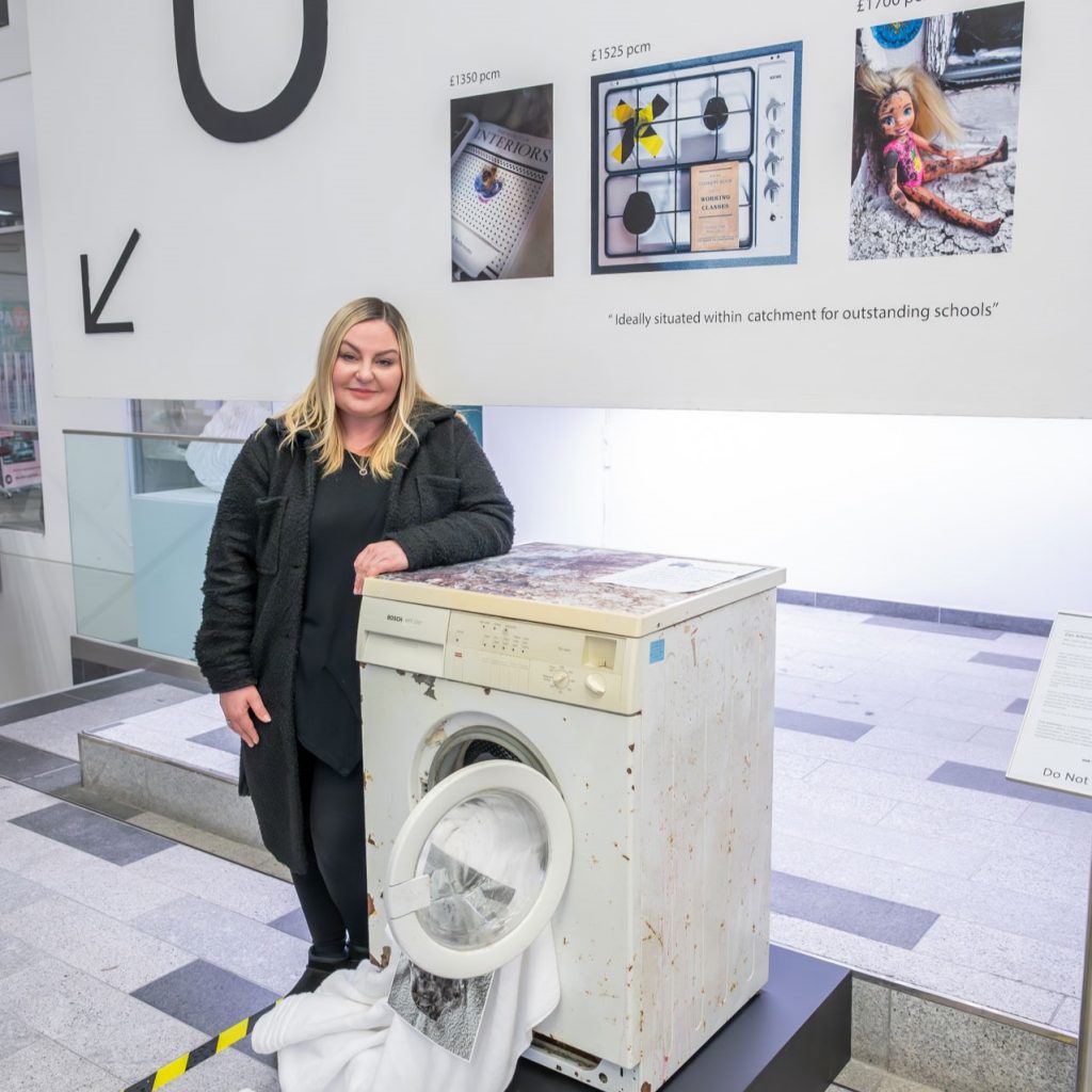 Graduate Scholar Zan Atkinson with her work in the New Adelphi Atrium, as part of Craig Easton's 'Is Anybody Listening? Our Time, Our Place' launch event in 2023.