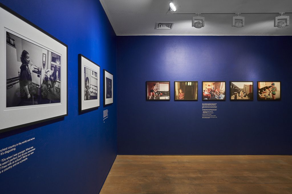 Installation view, Thatcher's Children at Opene Eye Gallery, Original black & white images alongside coloured images against a navy blye background. 