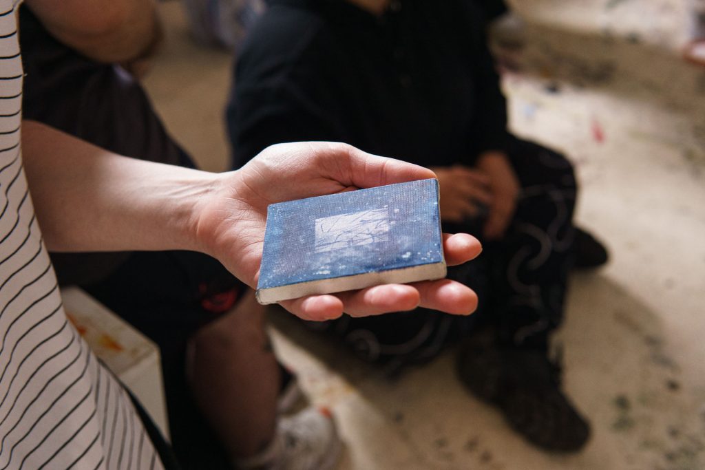 Steph Fletcher holding one of Jess Robinson's small artworks in hand.