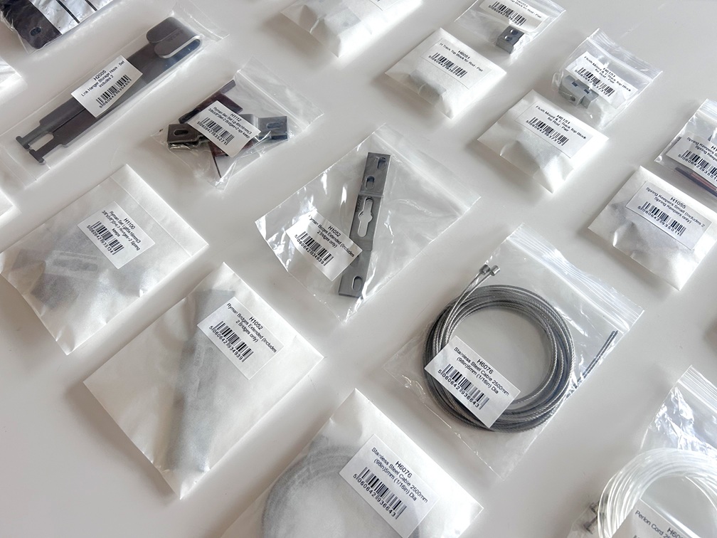 an image showing small metal fixings in bags, used for artworks. Some are in plastic bags, some in paper bags, demonstrating a sustainable switch