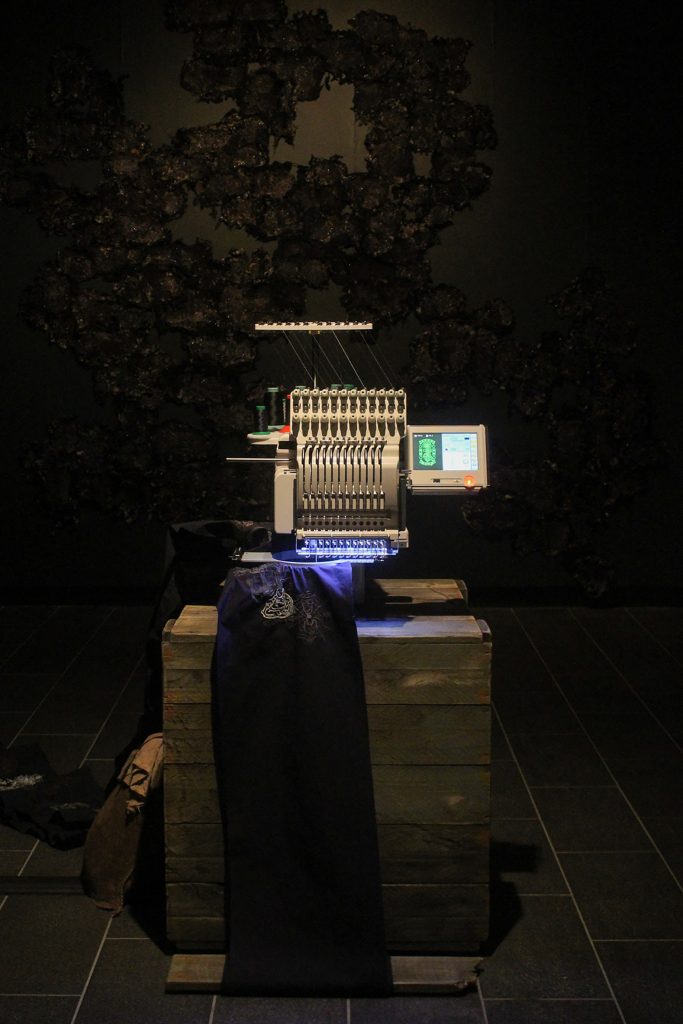 An automatic embroidery machine in a darkened room