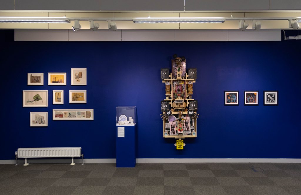 Four different artworks/artwork series' against a blue gallery wall.