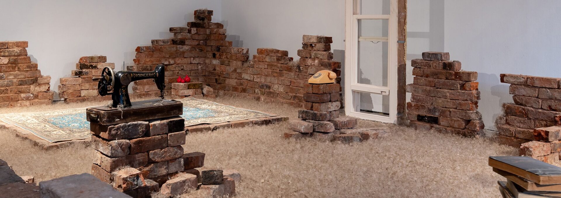 Bricks built in piles around room, with a rug and telephone in the centre.