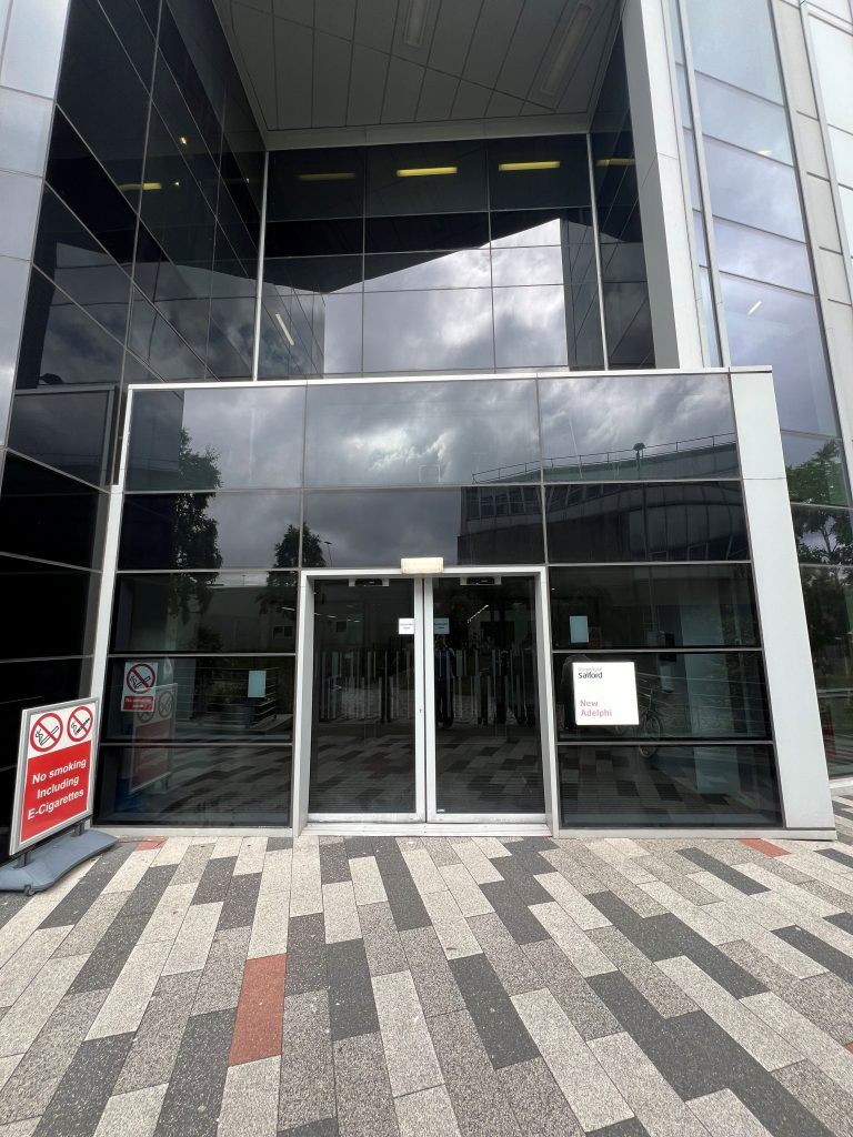 Entrance to a large building with blacked out glass and a automatic door entry.